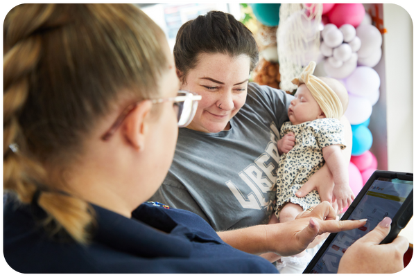 Parent holding newborn signing up to Kids Planet Nursery